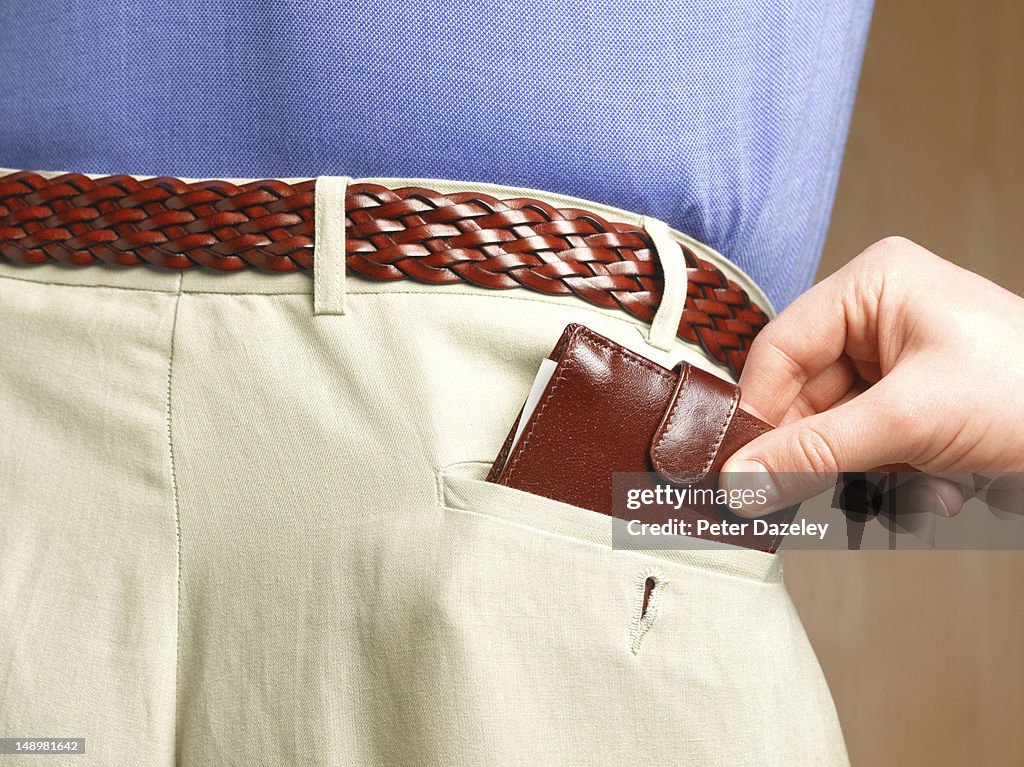 Hand removing the wallet from a man's pocket