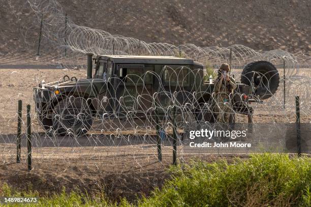 Texas National Guard soldier photographs media while on guard duty at an emptied-out migrant camp at the U.S.-Mexico border on May 13, 2023 to El...