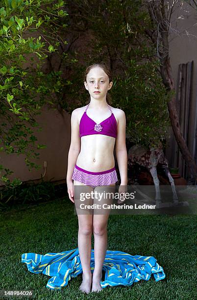 young girl standing in grass with arms at side - young girl swimsuit stockfoto's en -beelden