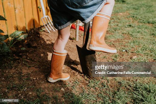 a child digs in a garden with a spade - bottomless girl stock pictures, royalty-free photos & images