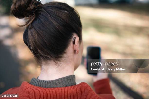 woman with hearing aid using smartphone - hearing aid stock pictures, royalty-free photos & images