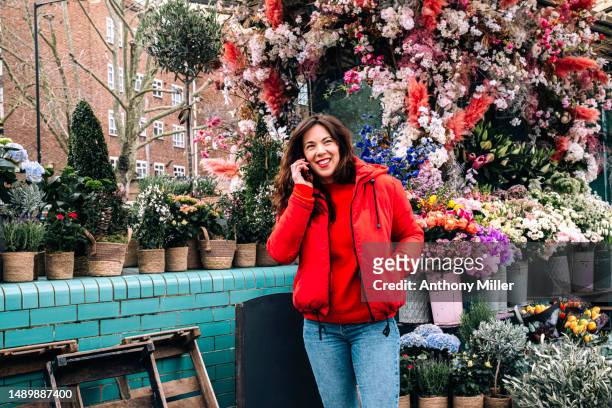 woman talking on smartphone in front of florist - botanist stock pictures, royalty-free photos & images