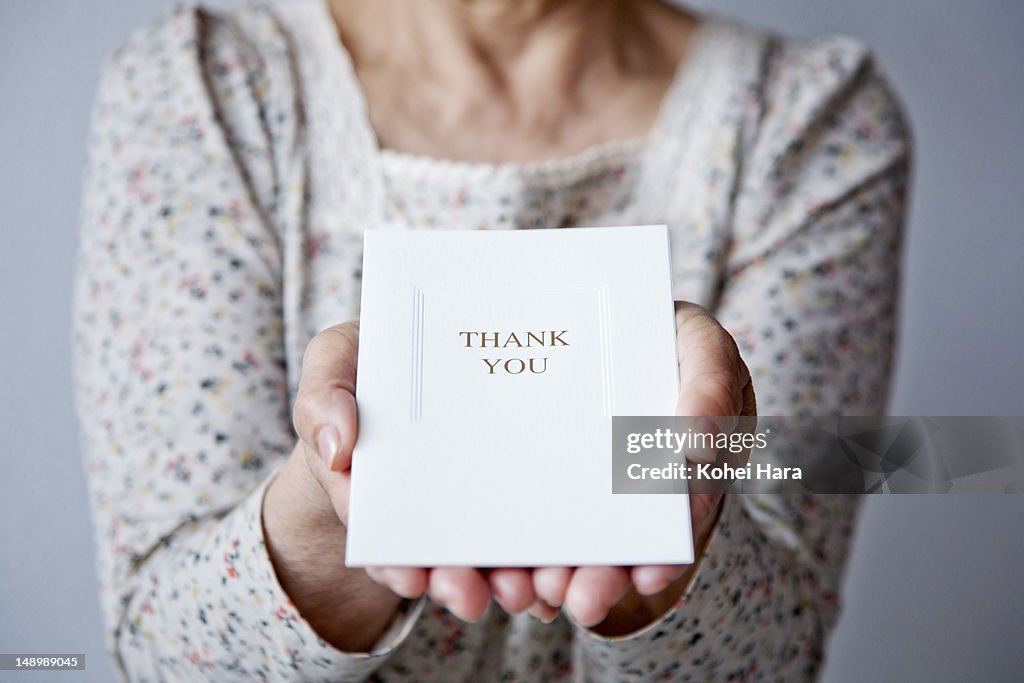 An elderly woman holding a card
