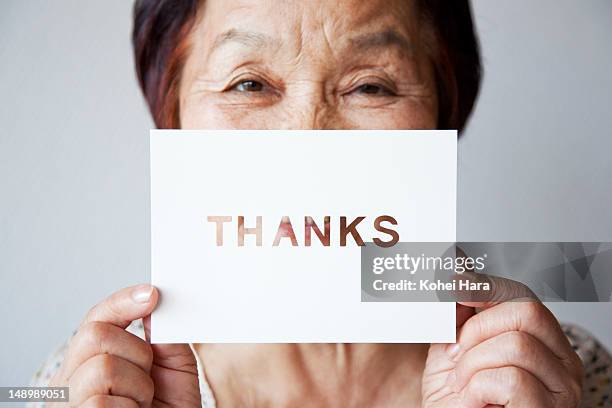 an elderly woman holding a card - thank you fotografías e imágenes de stock