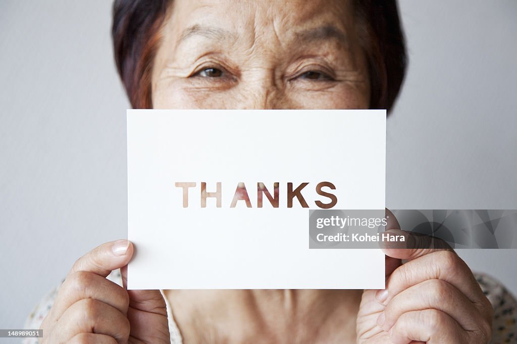 An elderly woman holding a card