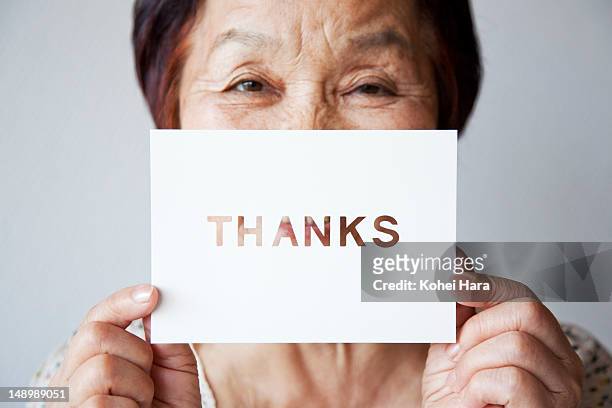 an elderly woman holding a card - woman gratitude stock pictures, royalty-free photos & images