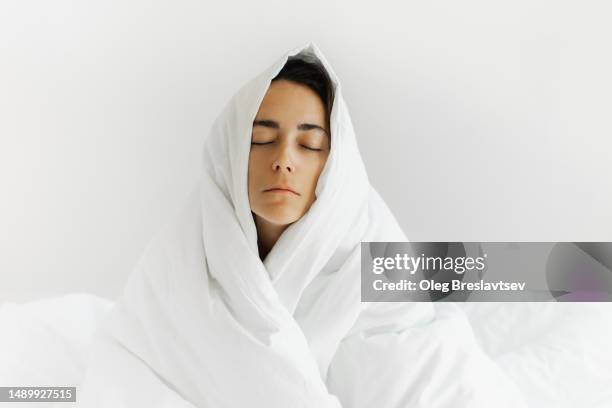 woman suffering from insomnia. alone at home in depression, covered in blanket in bedroom - avvolto foto e immagini stock