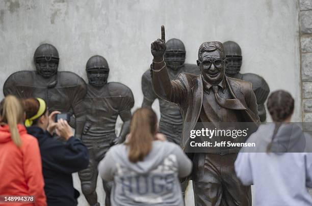 Visitors gather around the statue of former Penn State University football coach Joe Paterno stands outside Beaver Stadium July 21, 2012 in State...