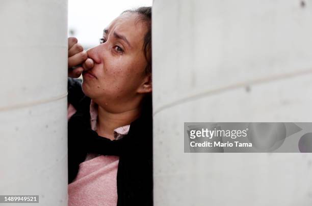 Colombian immigrant pauses as she recounts how her family was threatened, forcing them to leave Colombia, as she stands at a makeshift camp between...