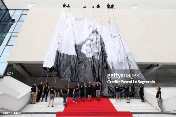 Workers install the official Poster of the 76th Cannes Film Festival at Palais des Festivals on May 14, 2023 in Cannes, France.
