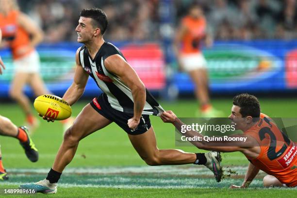 Nick Daicos of the Magpies handballs whilst being tackled by Josh Kelly of the Giants during the round nine AFL match between Collingwood Magpies and...