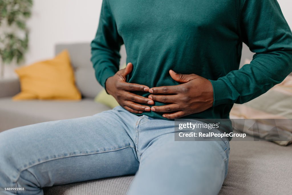 Young African American Man Suffering from Stomach Pain at Home