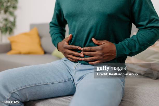 young african american man suffering from stomach pain at home - fart imagens e fotografias de stock