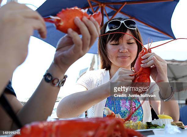 Chinese tourist Anna Ng enjoys freshly cooked Maine lobsters at the Portland Lobster Company on July 21, 2012 in Portland, Maine. A mild winter and...
