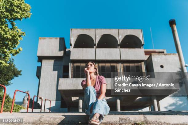 pensive girl sitting in an urban context - la mancha bildbanksfoton och bilder