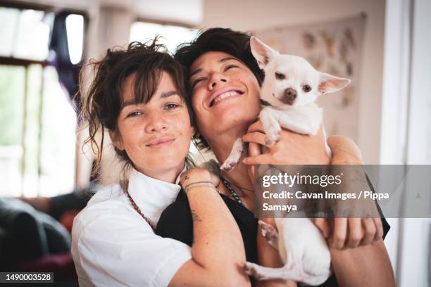 joyful queer interracial family moment of couple with dog at home - polyamory stock-fotos und bilder
