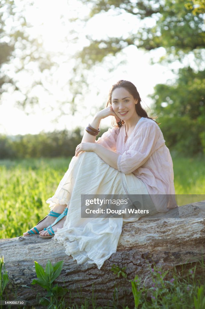 Portrait of woman sitting on tree trunk.