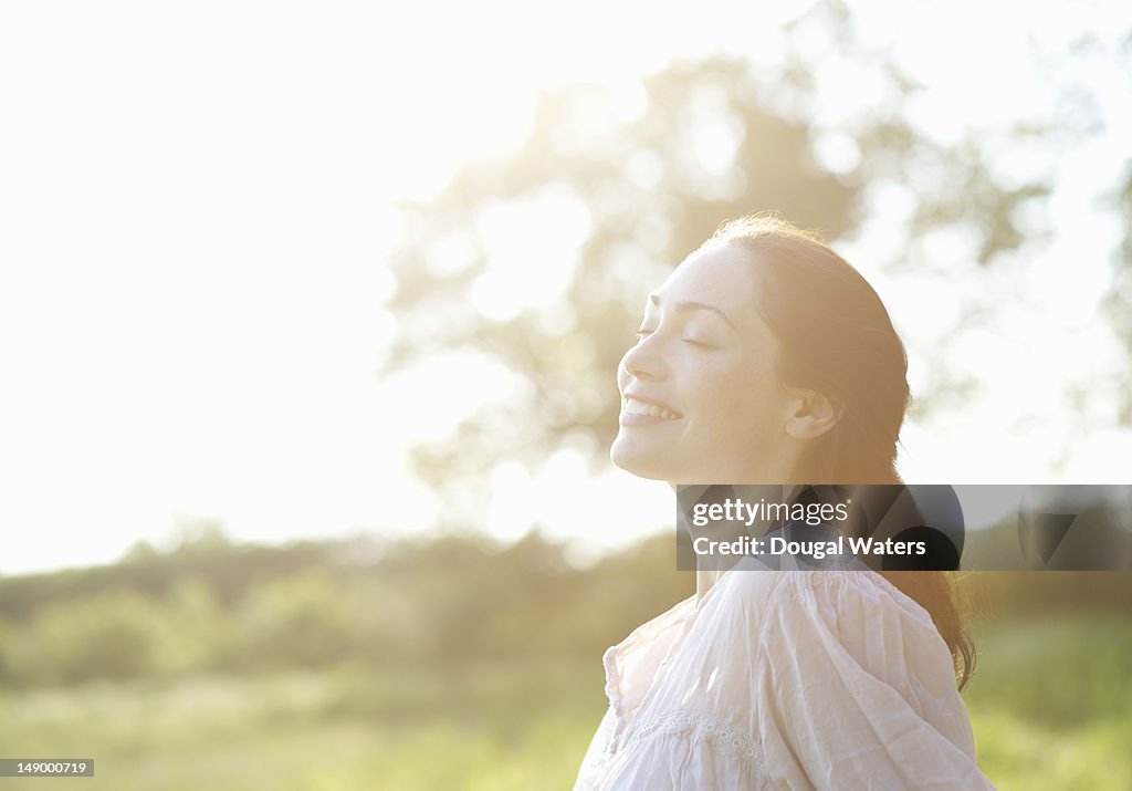 Profile of woman with eyes closed in countryside.