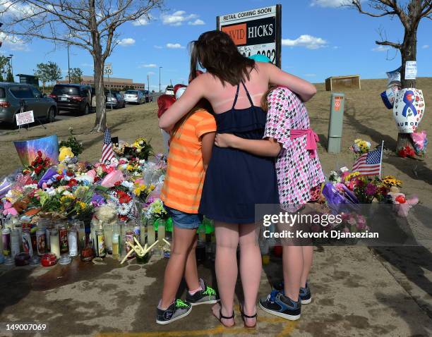 Sisters hug at a makeshift memorial across the street from the Century 16 movie theater the day after a gunman killed 12 people and injured 59 during...