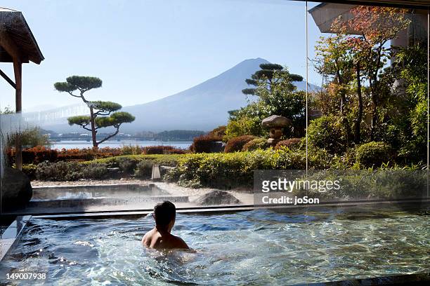 man soaking in an indoor hot spring pool - luxury travel stock-fotos und bilder