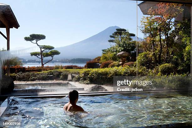 travel poster to japan man soaking in an indoor hot spring pool - japan travel stock pictures, royalty-free photos & images