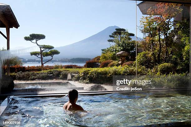 man soaking in an indoor hot spring pool - in a japanese garden stock pictures, royalty-free photos & images