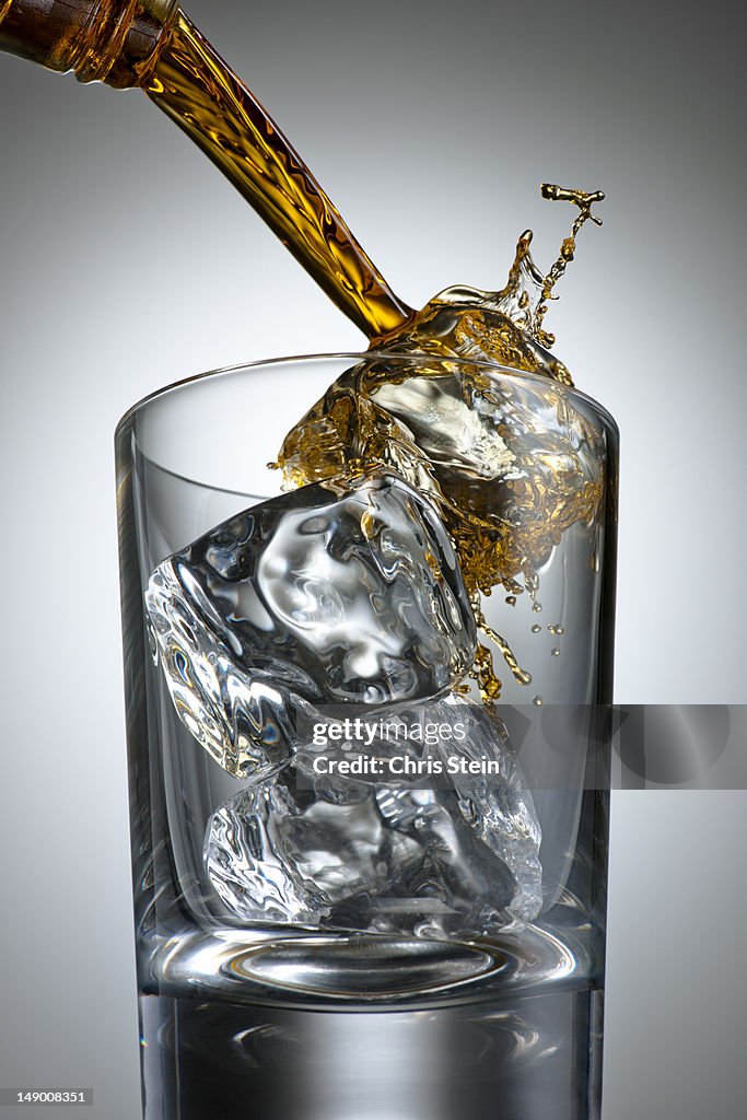 Brown Alcohol pouring and splashing into a glass