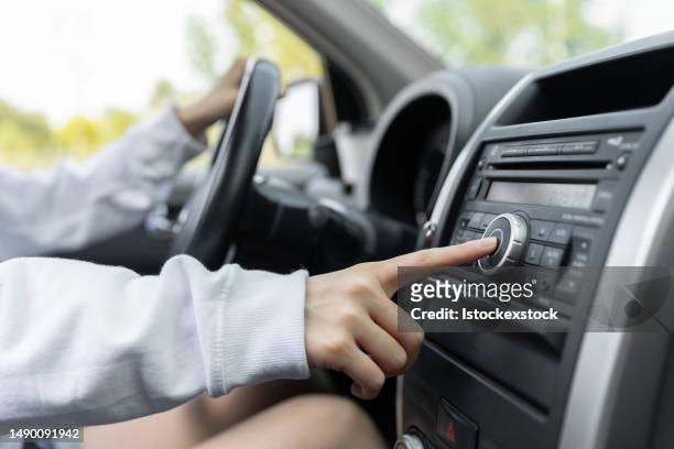 mujer girando botón de radio en el coche - auto radio fotografías e imágenes de stock