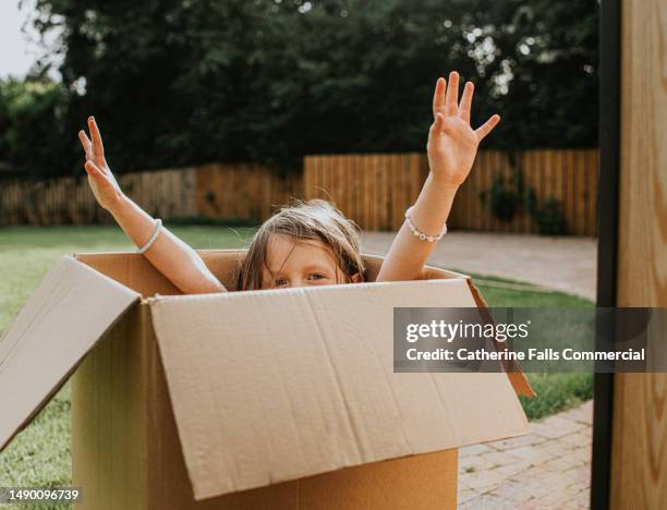 young girl playfully reaches out of a large cardboard box - removing shoes stock pictures, royalty-free photos & images