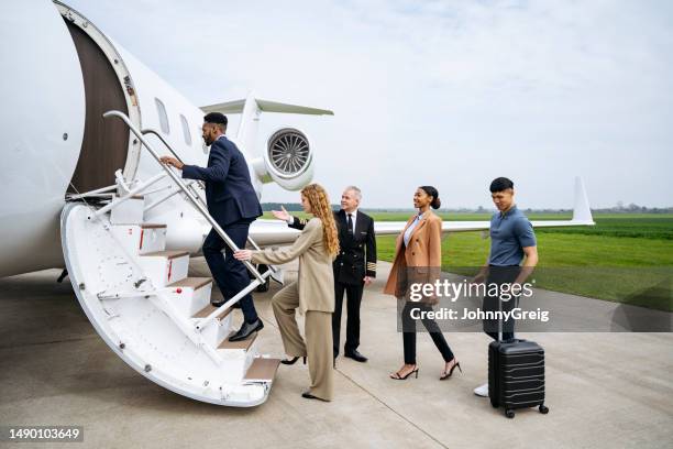 diverse group of young travellers moving up jet airstair - corporate jet stock pictures, royalty-free photos & images