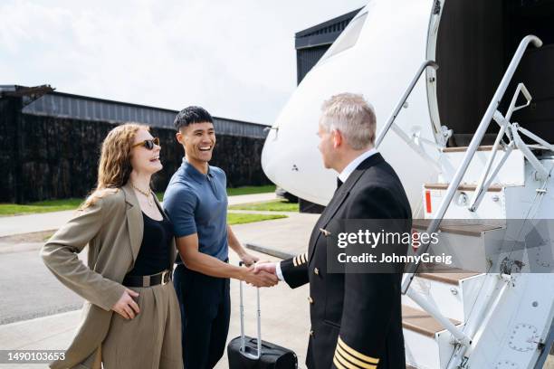 affluent young couple greeted by private jet pilot - berkshire england stock pictures, royalty-free photos & images