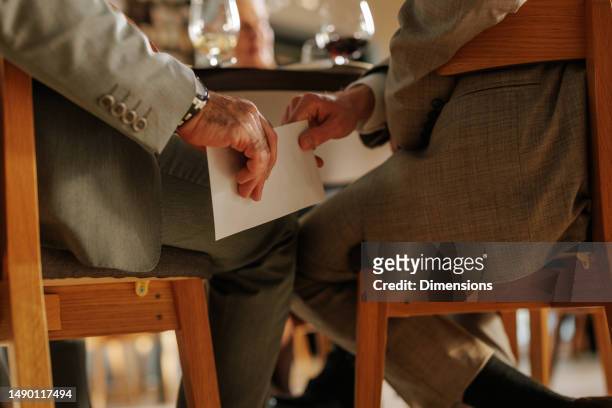 close up of businessperson handing envelope to man. - corruption stock pictures, royalty-free photos & images