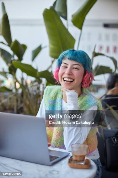 smiling young woman with colorful hair working with laptop computer in cafe. - generation z laptop stock pictures, royalty-free photos & images