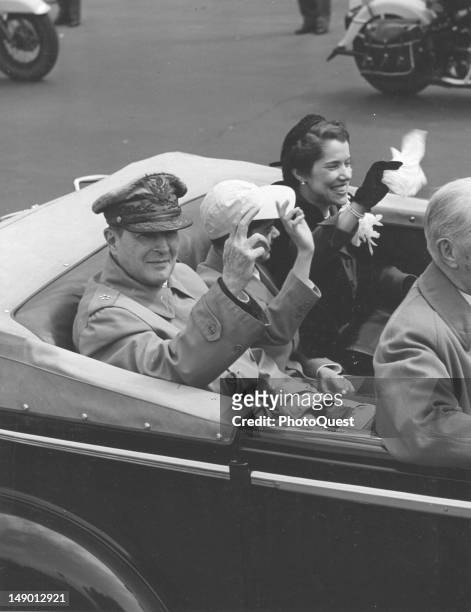 American military commander General Douglas MacArthur , his son Arthur MacArthur IV, and wife, Jean MacArthur wave from an open-top limousine at...