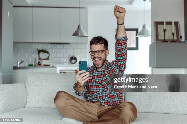 a smiling man holding a mobile phone and celebrating success - celebrate yourself bildbanksfoton och bilder