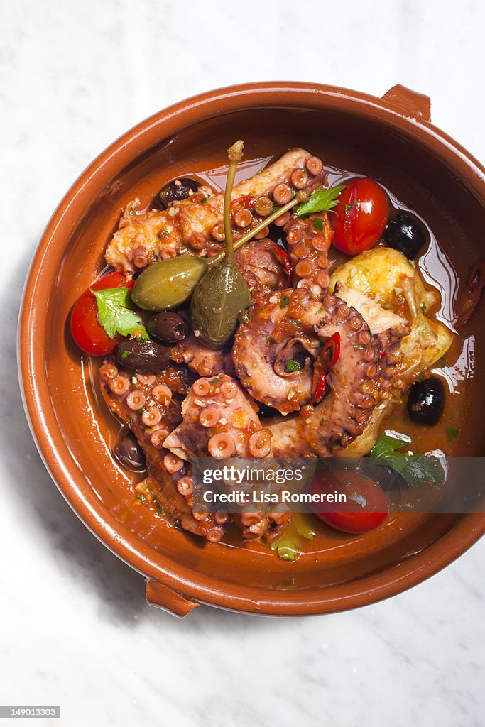 Serving of octopus with potatoes, capers, tomatoes