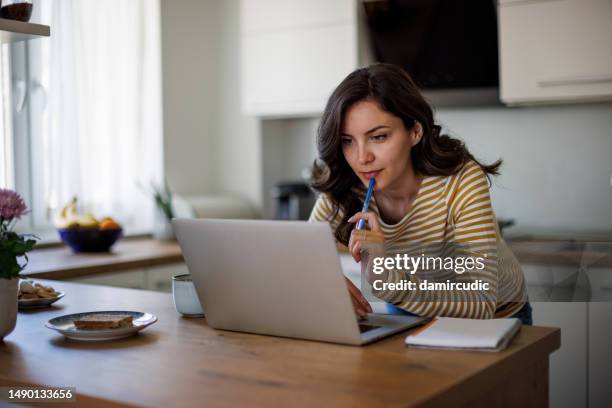 mujer joven usando un portátil mientras trabaja desde casa - meditar fotografías e imágenes de stock