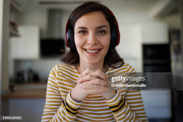 smiling confident young woman with bluetooth headphones having having video call at home - skypen stockfoto's en -beelden