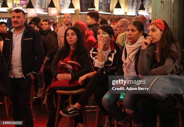 Local Turks react as preliminary Turkish national election results indicating a required runoff on March 28 are tallied and announced on a large...