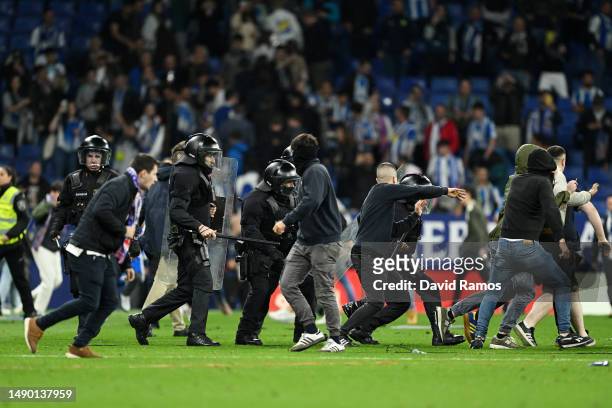 Police and RCD Espanyol fans are seen on the pitch after the LaLiga Santander match between RCD Espanyol and FC Barcelona at RCDE Stadium on May 14,...