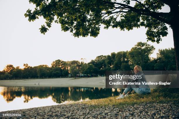 happy woman sitting by the lake at sunset - daily life in zagreb stock pictures, royalty-free photos & images