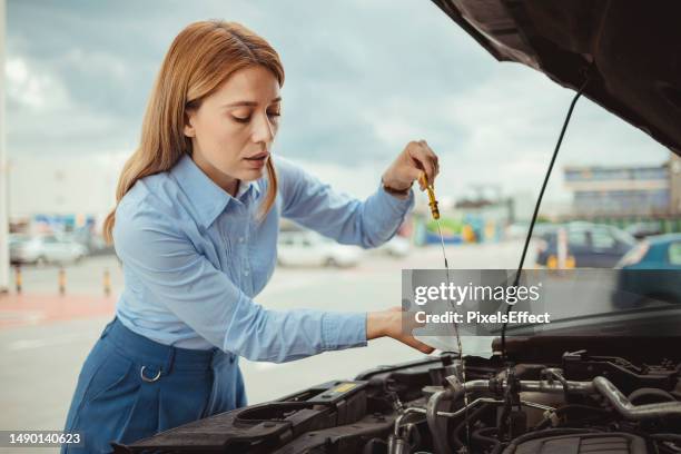 woman checking her car oil - óleo-de-motor imagens e fotografias de stock