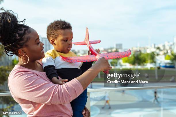 african american young mother playing with her son outdoors - model airplane stock pictures, royalty-free photos & images