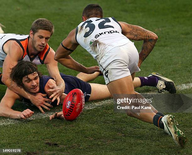 Dylan Roberton of the Dockers contests the ball against Callan Ward and Gerlad Ugle of the Giants during the round 17 AFL match between the Fremantle...