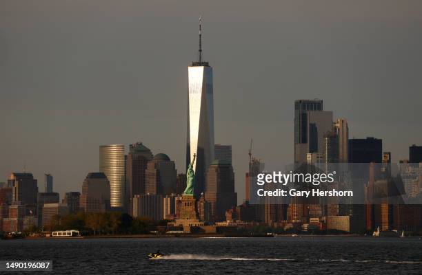 The sun sets on the skyline of lower Manhattan and One World Trade Center behind the Statue of Liberty in New York City on May 14 as seen from Jersey...