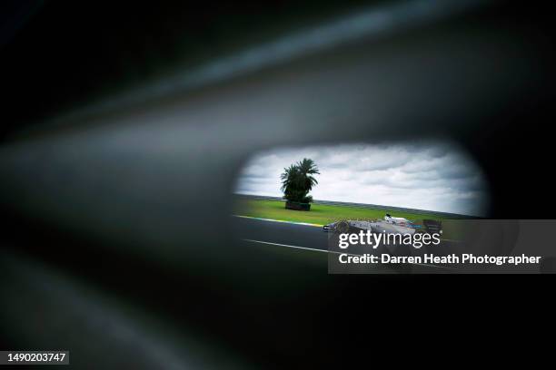 Seen through a hole in a crash barrier, Brazilian Williams Formula One racing team racing driver Felipe Massa driving his FW36 car at speed past a...