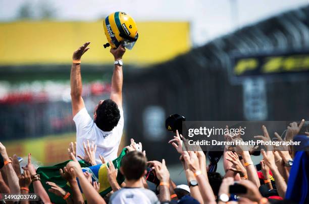 Brazilian fan of ex-Formula One racing driver Ayrton Senna displays his admiration for his hero by raising a replica crash helmet above his head...
