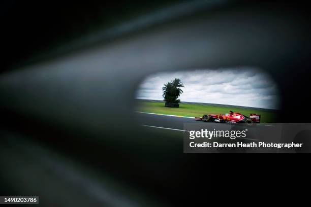 Seen through a hole in a crash barrier, Spanish Scuderia Ferrari Racing Formula One racing team racing driver Fernando Alonso driving his F14 T car...