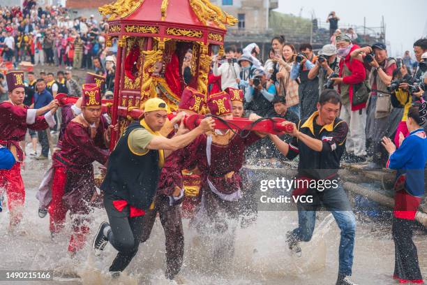 Pilgrims carry a sedan chair holding a statue of the sea goddess Mazu during a worshiping ceremony on May 14, 2023 in Ningde, Fujian Province of...