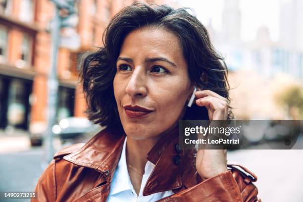 fashionable woman walking to the office listening voice messages on earphones - in ear headphones stock pictures, royalty-free photos & images